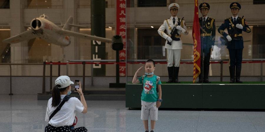 A child salutes for a photo near statues of Chinese military honor guards at the military museum in Beijing. 