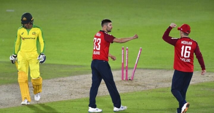 England's Mark Wood, center, celebrates with captain Eoin Morgan, right, the dismissal of Australia's Alex Carey, left, during the first Twenty20 cricket match.